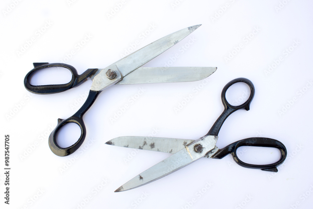 This high-resolution photograph captures an open pair of well-used scissors with black handles against a pristine white background. The wear on the blades suggests frequent use, making this image suit This high-resolution photograph captures an open pair of well-used scissors with black handles against a pristine white background. The wear on the blades suggests frequent use, making this image suit