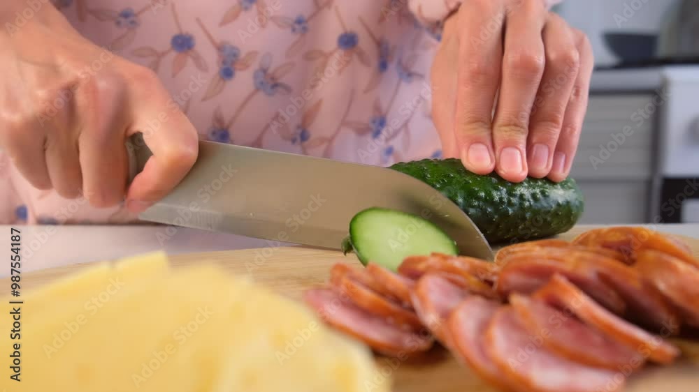 Woman cooking cutting cucumber on thin slices on wooden board. Hands of woman cook sandwiches on kitchen at home. Meat delicacy for cooking pizza and other dishes. Preparing snack food. Woman cooking cutting cucumber on thin slices on wooden board. Hands of woman cook sandwiches on kitchen at home. Meat delicacy for cooking pizza and other dishes. Preparing snack food.