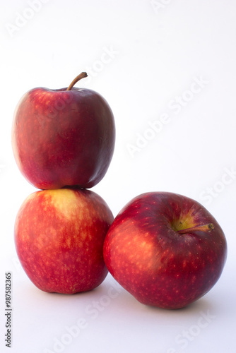 Three Red Apples in the white background. Apples also provide copper to produce red blood cells, vitamin A to maintain healthy organ functioning, vitamin E to reduce inflammation.