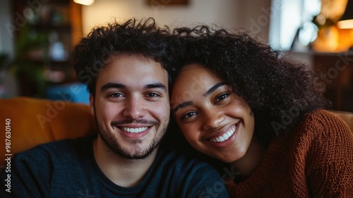 In their home, a young couple smiles for a cozy and intimate portrait.