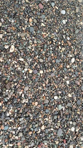 Beach pebbles on the sea shore, top view, white waves, Batumi, Black Sea