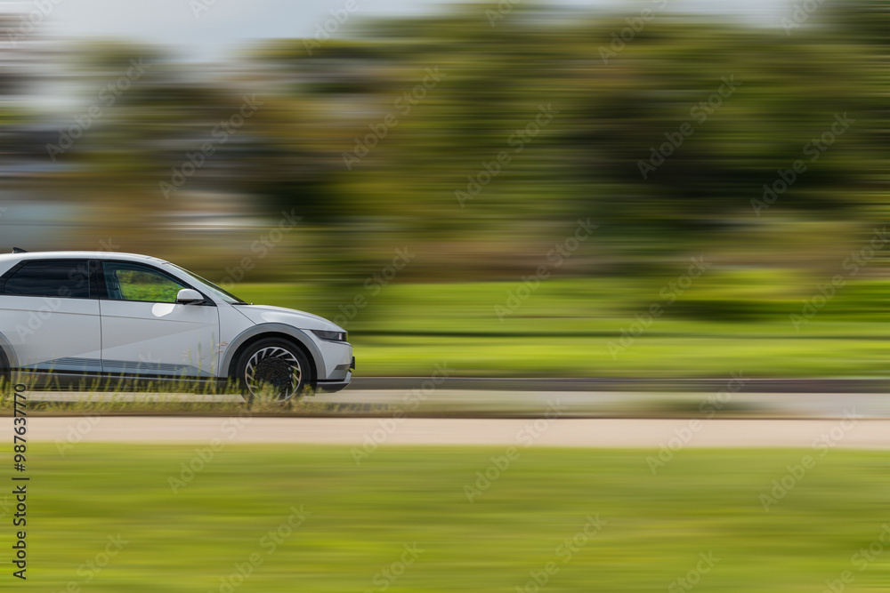 Car on speed blurred background. A white car is driving fast on the highway with green grass in the background Car on speed blurred background. A white car is driving fast on the highway with green grass in the background