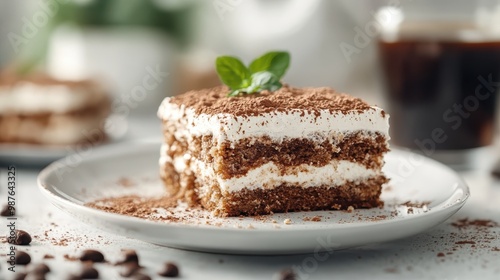 A perfectly layered tiramisu dessert garnished with a fresh mint leaf, served on a white plate, showcasing a delicious blend of coffee, cream, and cocoa flavors.