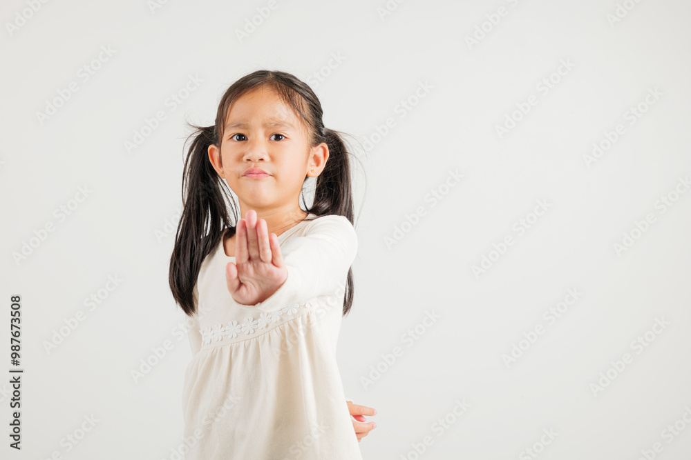 Asian portrait cute young kid girl smiling doing show stop sign gesture with palm of hand but unhappy face studio shot isolated on white background, kindergarten children doubt with copy space Asian portrait cute young kid girl smiling doing show stop sign gesture with palm of hand but unhappy face studio shot isolated on white background, kindergarten children doubt with copy space