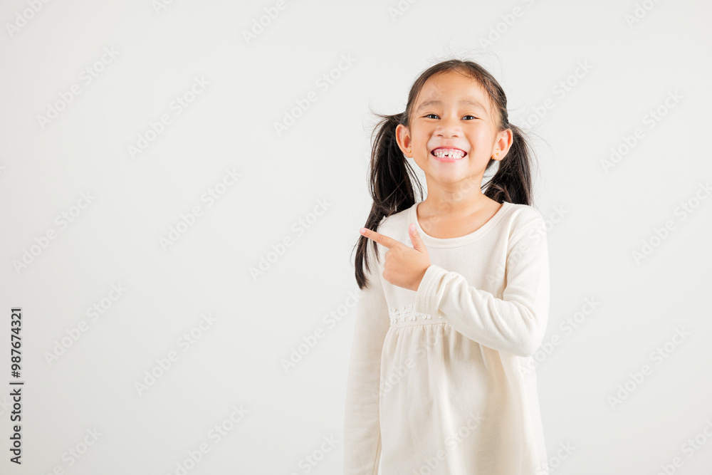 Happy Asian portrait cute young kid girl smiling indicate finger empty space, studio shot isolated on white background, Thai kindergarten child pointing index out with copy space Happy Asian portrait cute young kid girl smiling indicate finger empty space, studio shot isolated on white background, Thai kindergarten child pointing index out with copy space