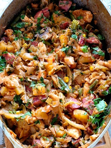 vegetable stew with chicken and sausages in a frying pan