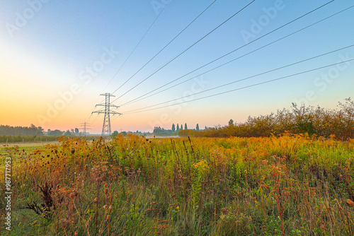 Power Lines and Transmission Towers in Rural Landscape at Sunrise