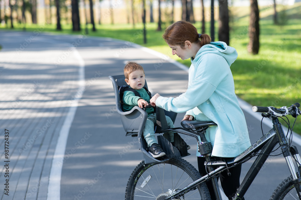 Obraz premium Caucasian woman rides bicycle with one-year-old son in park. 