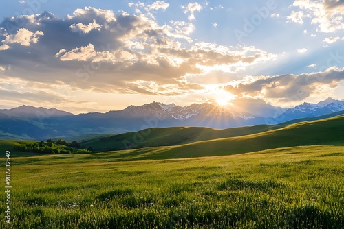 Beautiful sunset over a field with green grass and mountains in the background