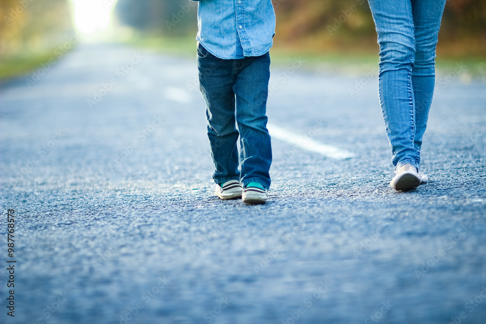 A Happy parent with child are walking along the road in the park on nature travel A Happy parent with child are walking along the road in the park on nature travel