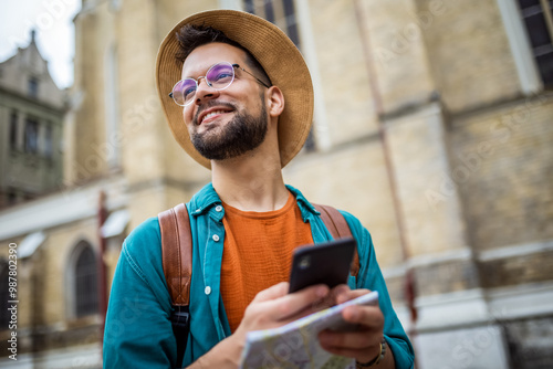 Fotografie Male tourist looking at map on his phone while touring a foreign city