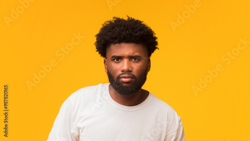 Serious afro man posing over orange studio background