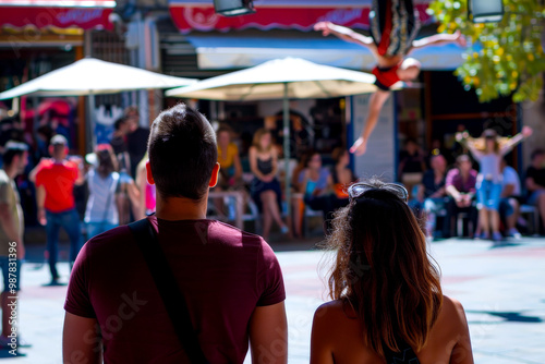 A couple watching a street performer's acrobatic act.