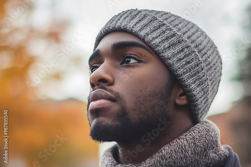 Young black man wearing winter clothes is looking up with hope