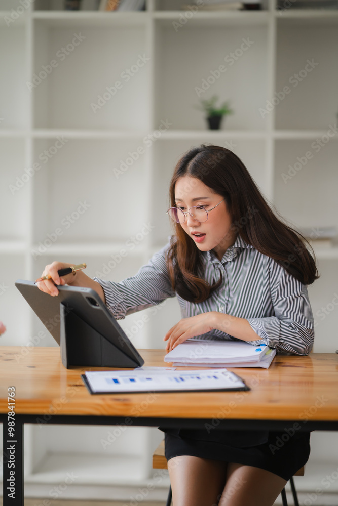 Focused Determination: A young businesswoman, dressed in a professional outfit, leans forward with intensity, studying a tablet screen intently. Her expression conveys focus, determination, and a comm Focused Determination: A young businesswoman, dressed in a professional outfit, leans forward with intensity, studying a tablet screen intently. Her expression conveys focus, determination, and a comm