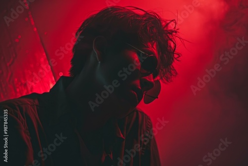 Portrait of a young man wearing sunglasses illuminated with red light