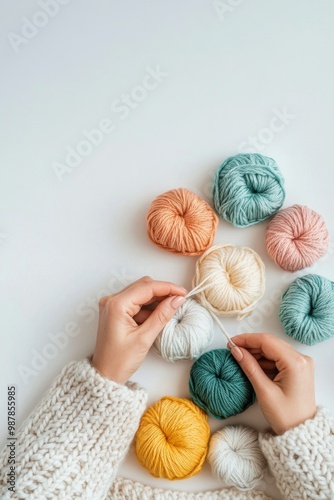 A person crafting with colorful yarn balls on a light background during a cre...