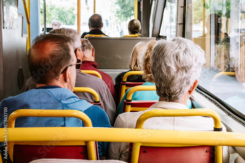 A group of elderly people sitting in the back seats of a bus, looking out the windows during a sightseeing excursion.