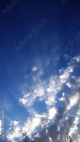 Vertical stock time-lapse video of a natural blue sky scenario with clouds between which the sun's sunset rays are shining full hd with fps 25 frames. Natural Surroundings Background. photo