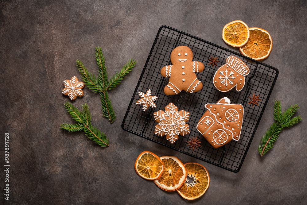Set of Christmas gingerbread cookies on a cooling rack with dried orange slices and spruce branches, brown rustic background. Top view, flat lay, copy space. Set of Christmas gingerbread cookies on a cooling rack with dried orange slices and spruce branches, brown rustic background. Top view, flat lay, copy space.
