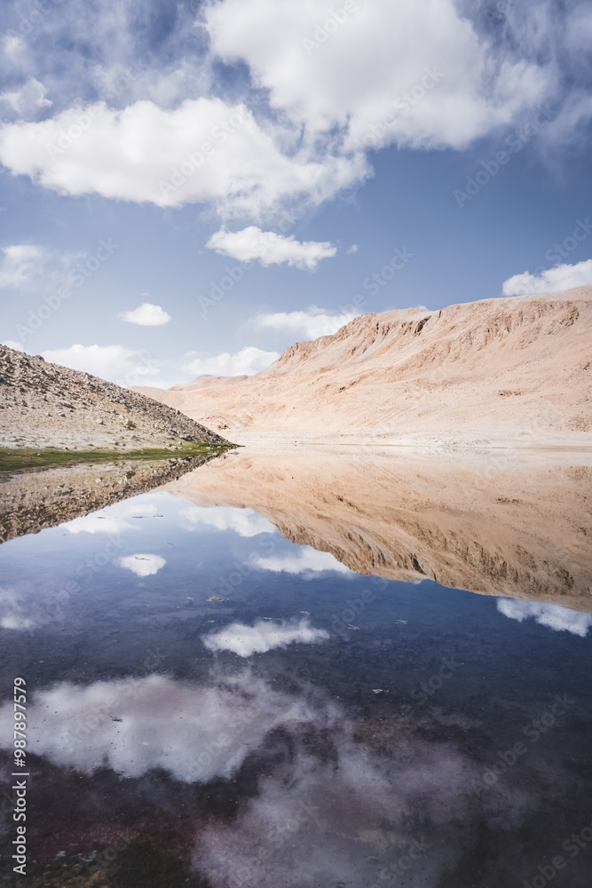 Lake Chukurkul with a mirror surface reflects rocky mountains and blue sky in the Tien Shan mountains in Pamir in Tajikistan, mirror landscape for the background