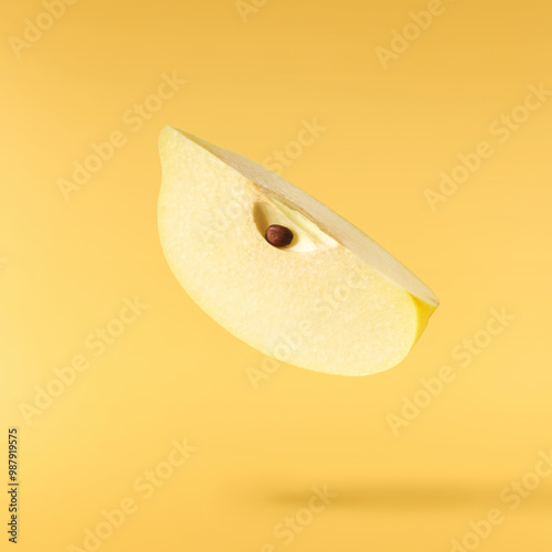 Fresh ripe yellow Quince fruit  falling in the air isolated on yellow background. Food levitation or zero gravity conception