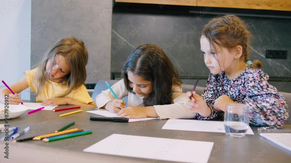 Three girls are sitting at the kitchen table in a modern apartment, drawing various pictures and having fun. The table is filled with colorful pencils, cookies, orange juice, and water, creating a Three girls are sitting at the kitchen table in a modern apartment, drawing various pictures and having fun. The table is filled with colorful pencils, cookies, orange juice, and water, creating a