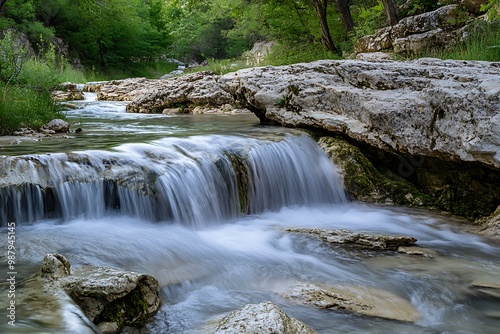 Serene waterfall in a forest, flowing over rocks in a lush green environment