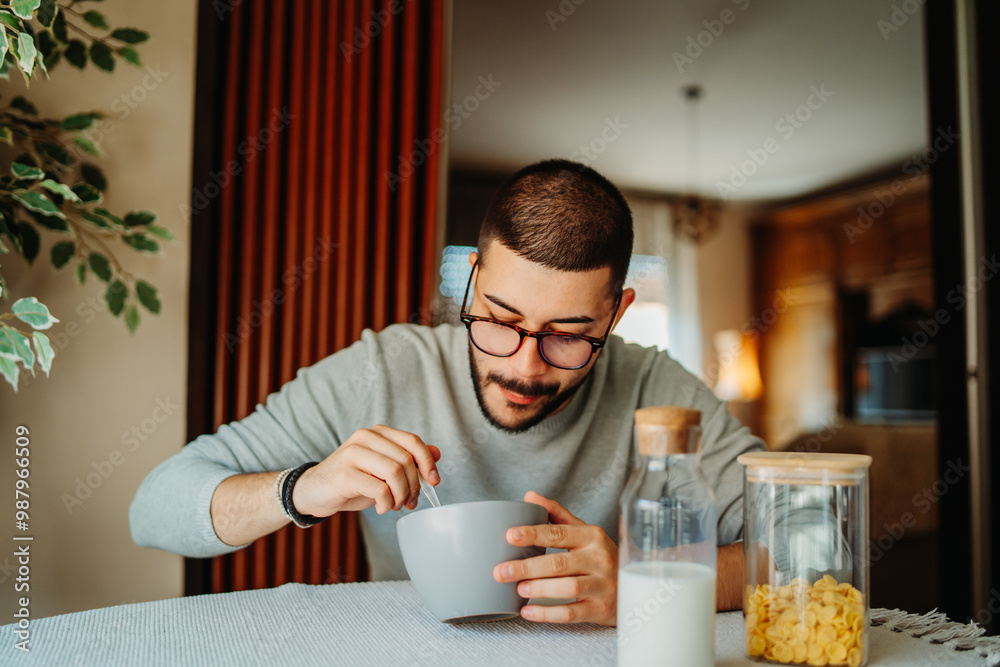 Young caucasian man eating corn flakes for breakfast at home Young caucasian man eating corn flakes for breakfast at home