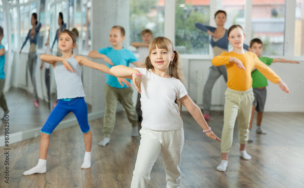 Obraz premium Girls with boys repeat teaches sequences of movements during training, train to perform electro dance, enjoys active hobby to favorite music. Unrecognizable female teacher administer conduct class