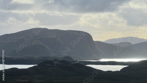 Mountain range with reflective water bodies and cloudy sky.