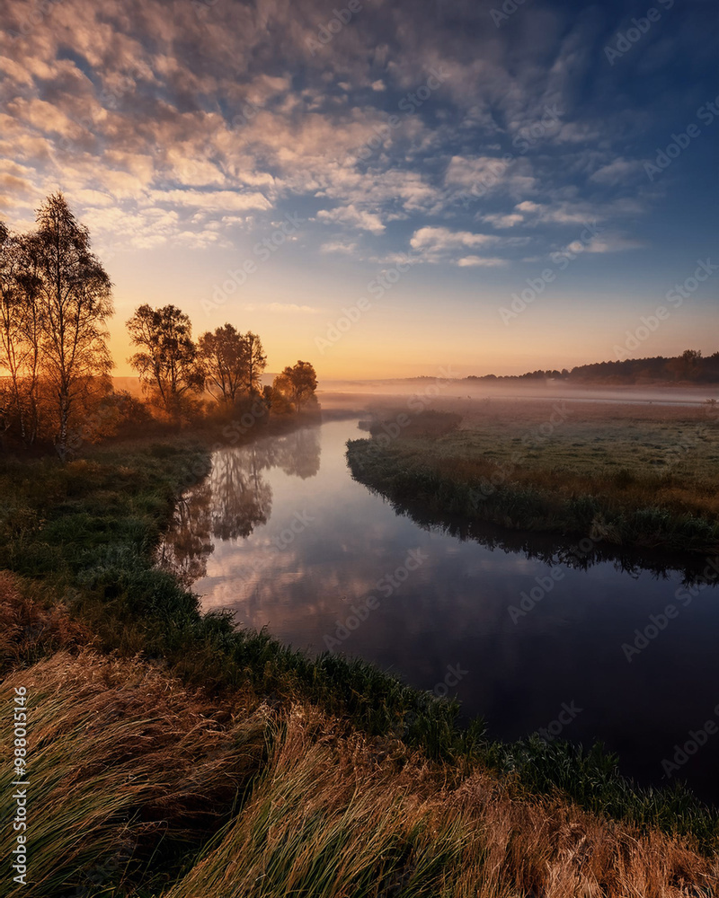 Fototapeta premium Scenic river flowing through misty landscape at sunrise