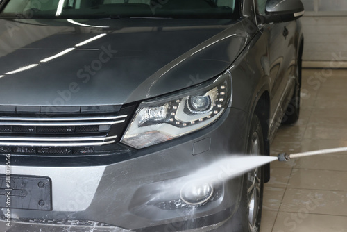 Washing auto with high pressure water jet at car wash, closeup