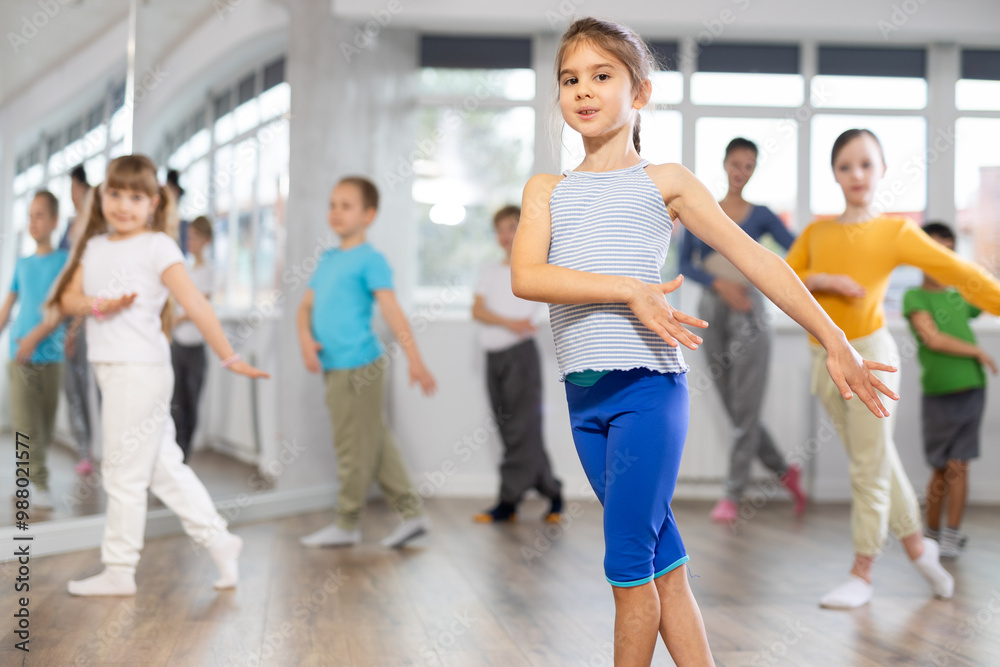 Fototapeta premium Children studying modern style dances with female teacher in dance class indoors