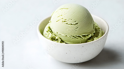 A scoop of green tea ice cream served in a white bowl with minimal garnish