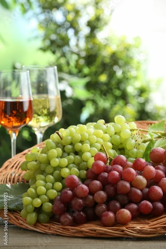 Fresh ripe grapes and glasses of wine on wooden table, closeup