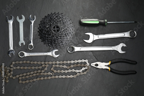 Canvastavla Parts of bicycle and tools on black table, flat lay