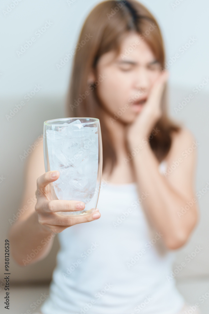 Teeth Sensitive to Cold concept. woman hold Ice Water glass and having toothache and pain after eat. Tooth Decay or Gum Disease, Grinding Teeth and Stress, Exposed Nerve Roots, Crack and Receding Gums Teeth Sensitive to Cold concept. woman hold Ice Water glass and having toothache and pain after eat. Tooth Decay or Gum Disease, Grinding Teeth and Stress, Exposed Nerve Roots, Crack and Receding Gums
