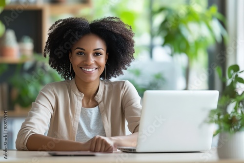 Smiling Successful African American Woman Sitting at Her Desk Working on a Laptop Computer