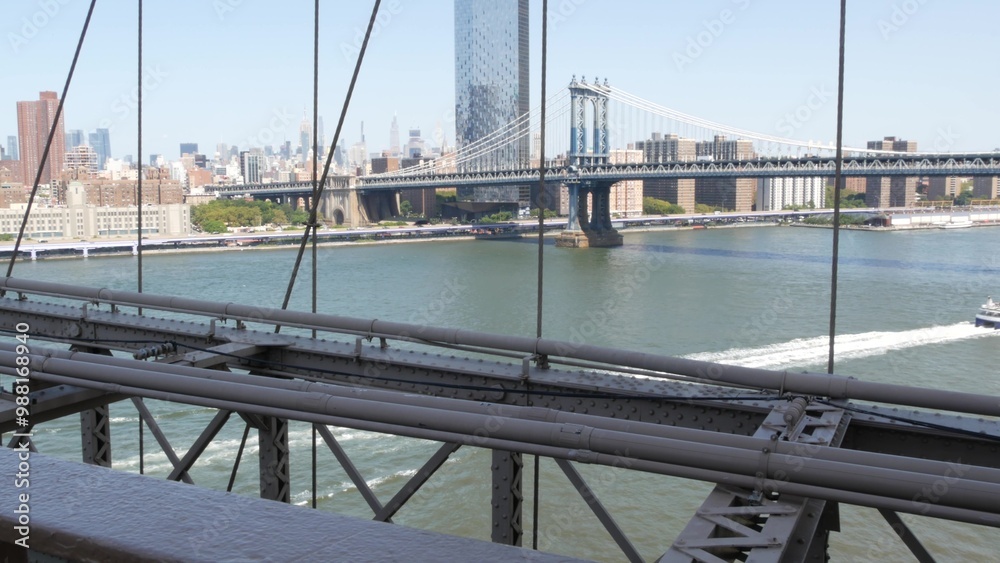 Naklejka premium New York City Manhattan Bridge from Brooklyn Bridge view. USA travel landmark, NYC skyline cityscape. Iconic architecture thru cables over East River water. Visit United States of America.
