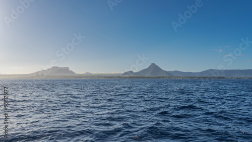 Wallpaper Mural Seascape. Ripples on the surface of the blue ocean. The coast of the island of Mauritius is visible in the distance. Picturesque mountains against a clear sky. Copy space. Torontodigital.ca