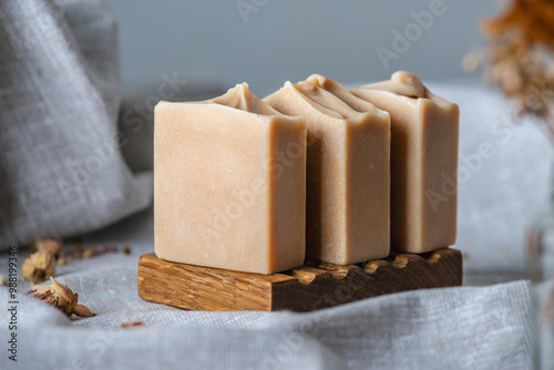 Delicate natural soap in pastel colors on a wooden soap dish on a background of gray fabric
