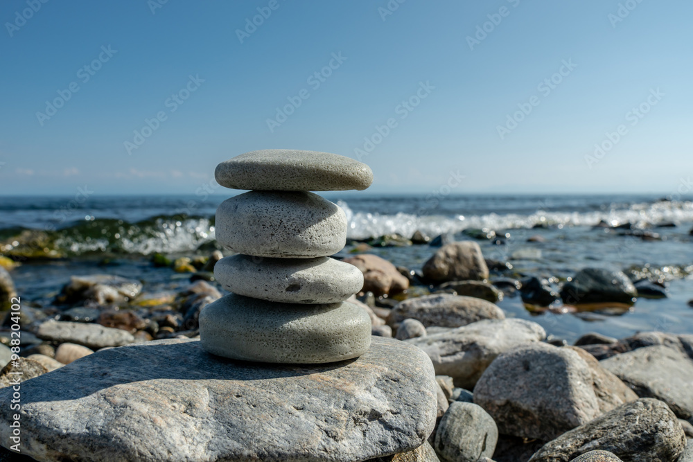 Fototapeta premium Handmade soap pieces in the shape of stones are stacked on top of each other on the shore of the sea or lake. Image of organic cosmetics in a natural environment