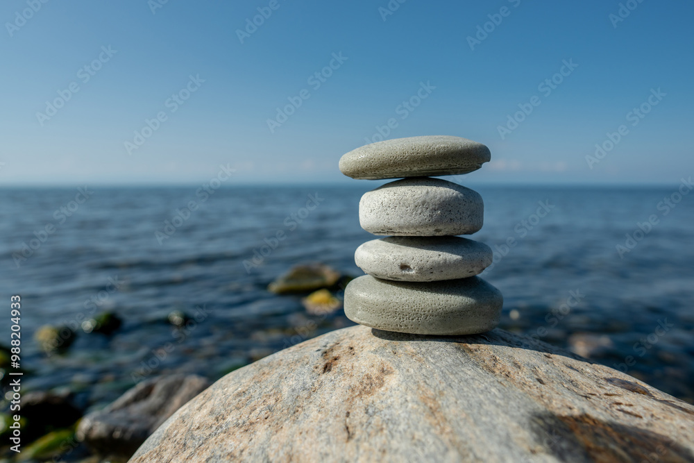Fototapeta premium Pieces of craft soap in the shape of stones are stacked on top of each other against the background of the sea or lake. Image of organic cosmetics in a natural environment