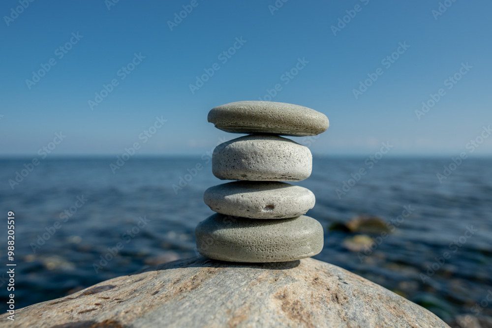 Fototapeta premium Pieces of craft soap in the shape of stones are stacked on top of each other against the background of the sea or lake. Image of organic cosmetics in a natural environment