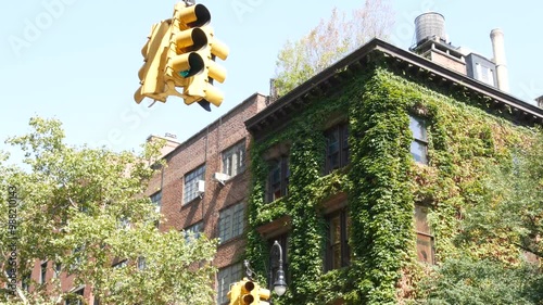 New York City Irving street crossroad, traffic light. Building architecture. Rooftop water tower, tank. Red brick house, Manhattan, United States. Green corner, ivy vine plant, leaves covered wall. photo