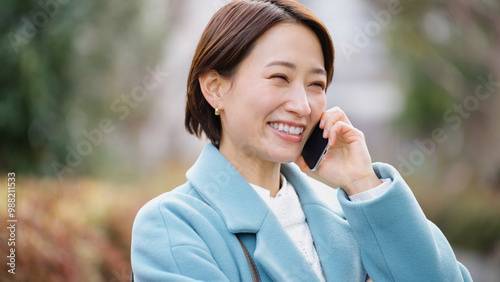 スマホで話す女性（冬服・上着・コート）