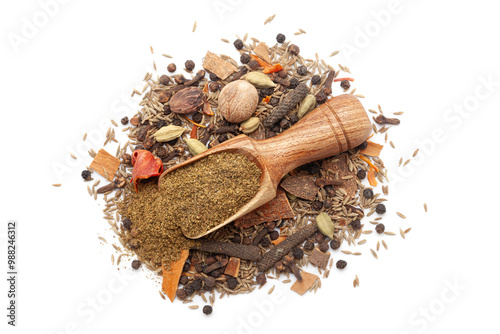 A wooden scoop filled with organic warming spices or whole Garam Masala powder, placed on a heap of whole spices, isolated on a white background. photo