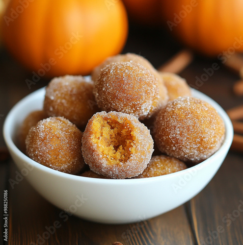 A bowl filled with golden brown fried dough balls coated in powdered sugar photo