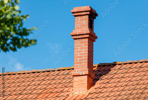 A brick chimney on a red roof